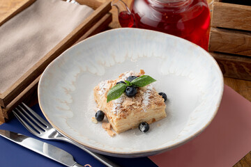 A portion of puff pastry napoleon cake in a wide restaurant dish, top view