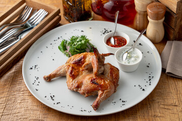 Whole quail in a restaurant on a wide white dish, top view