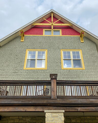 interesting red and grey shingled house with yellow window trim