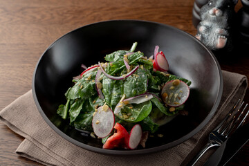 Summer salad with spinach and radish, dressed with crushed pistachio nuts