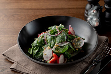 Summer salad with spinach and radish, dressed with crushed pistachio nuts