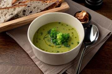 Green broccoli cream soup with olive oil and bread basket aside