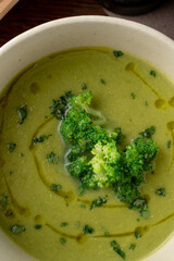 Close up green cream soup with olive oil swirls on it, soft light, autumn cozymeal