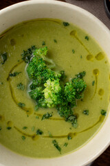 Close up green cream soup with olive oil swirls on it, soft light, autumn cozymeal