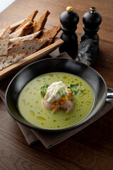 Cream soup with crab meat and shrimps on wooden table in a fancy fish restaurant, soft light, appetizing food commercial