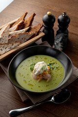 Top view of seafood cream soup with prawns in a fancy fish restaurant, appetizing food commercial, bread and spoon aside