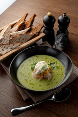 Top view of seafood cream soup with prawns in a fancy fish restaurant, appetizing food commercial, bread and spoon aside