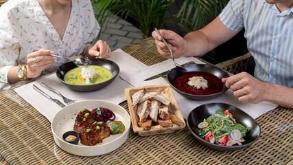An adult couple having lunch on a summer terrace of a posh restaurant, set table with fine dining meals, no faces