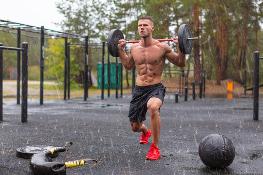 Full length photo of a man doing exercise lunges outdoors on a rainy day.