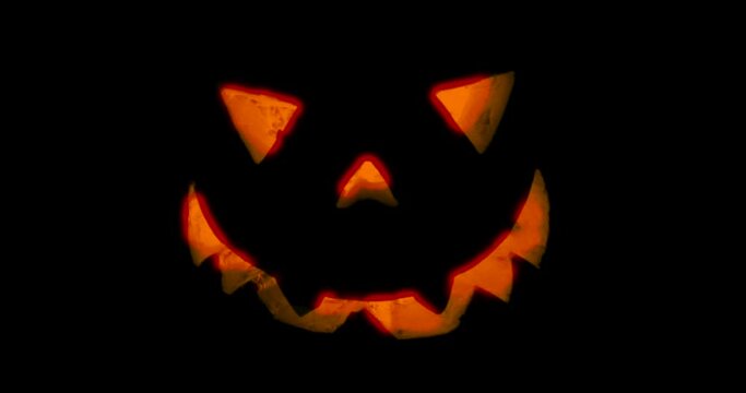 Pumpkin for Halloween glowing demon face in dark.  Scary Halloween pumpkin face 