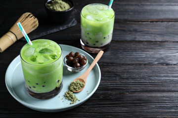 Tasty milk bubble tea with green matcha on black wooden table. Space for text