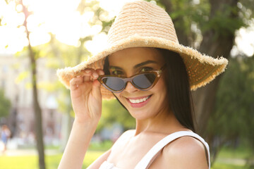 Beautiful young woman wearing stylish sunglasses in park