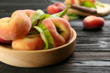 Fresh ripe donut peaches on black wooden table, closeup