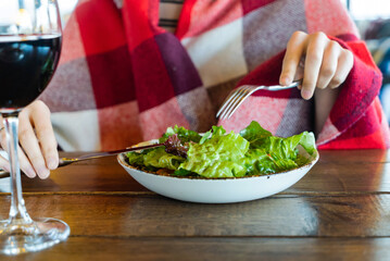 woman eating fresh salad  and drinking red wine
