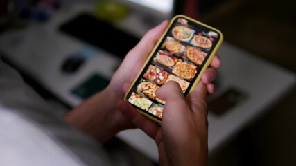 Ordering pizza using online delivery. A man orders food at home in an online store using a smartphone. Ordering pizza using a food delivery app. Online delivery, online store, home delivery.