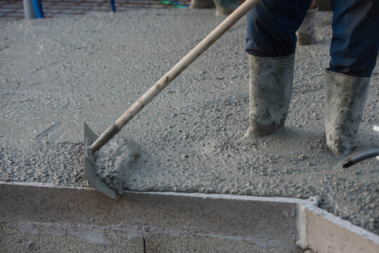 worker spreading concrete at construction site