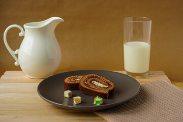 roll in a plate and a glass of milk and creamer