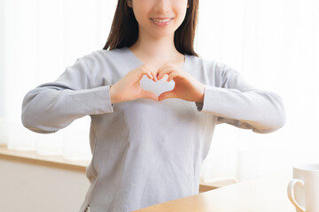 手でハートの形を作る若い女性