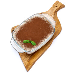 Traditional Italian Tiramisu dessert in glass baking dish on wooden cutting board isolated on white background with clipping path