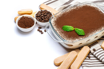 Traditional Italian Tiramisu dessert in glass baking dish and savoiardi cookies isolated on white