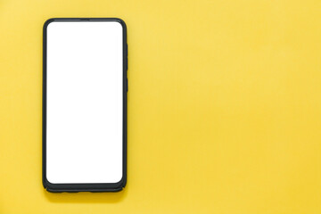 Top view of mockup black color smartphone with blank desktop on yellow background, copy space, flat lay