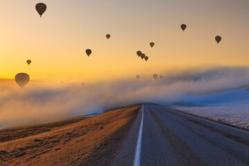 Fototapeta na wymiar Hot air balloons over the road at sunset. Path and adventure concept