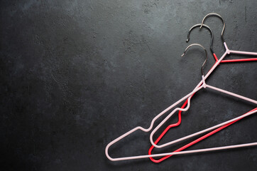 Red coat hangers on a dark concrete background. Copy space