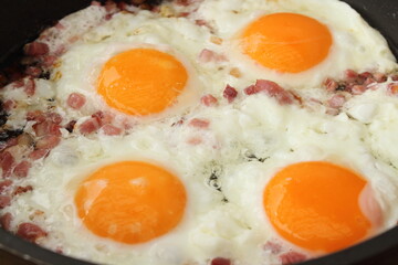 several fried eggs with bacon in the pan
