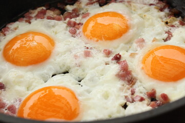 several fried eggs with bacon in the pan