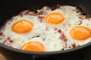 several fried eggs with bacon in the pan