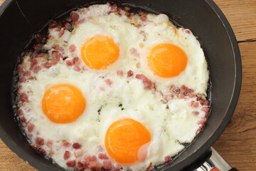 several fried eggs with bacon in the pan