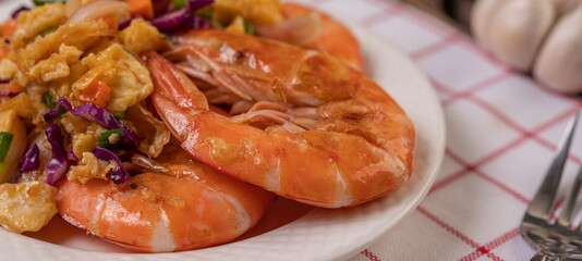 Fried shrimp with eggs in a white plate placed on a cloth with a fork.