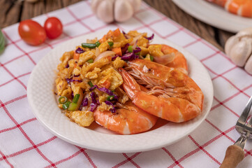 Fried shrimp with eggs in a white plate placed on a cloth with a fork.