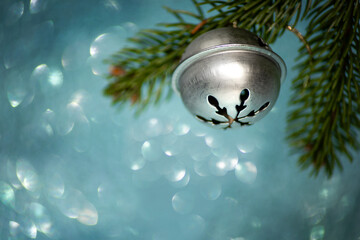 Fototapeta premium Bell on a Christmas tree branch on a blue background with bokeh