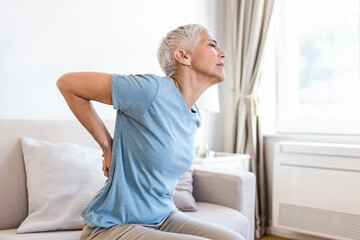 Matur Woman suffering from lower back pain. Mature woman resting with back pain. Female lower back...