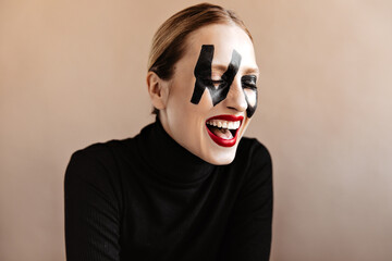Unusual woman with written word no on face laughs. Portrait of girl with red lipstick dressed in...