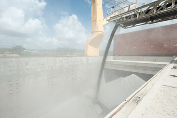 Loading of ship cargo gold with bulk cargo bauxite. Dusty atmosphere.