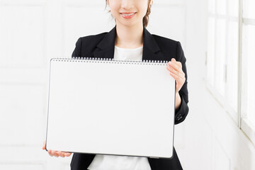 大きいスケッチブックを持つ若いビジネスウーマン