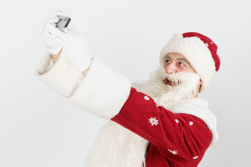 Santa Claus poses, makes a selfie on a mobile phone. Isolated background