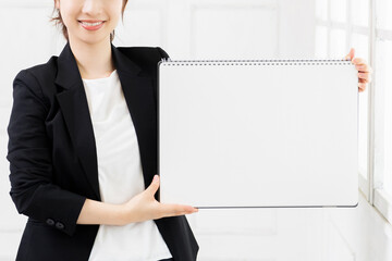 大きいスケッチブックを持つ若いビジネスウーマン