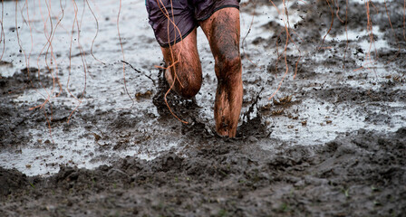 Mud race runner, man running in mud. Runners during extreme obstacle races. Active life and sport...