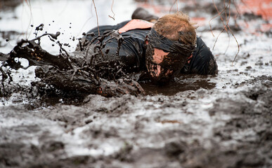 Mud race runner, man running in mud. Runners during extreme obstacle races. Active life and sport...