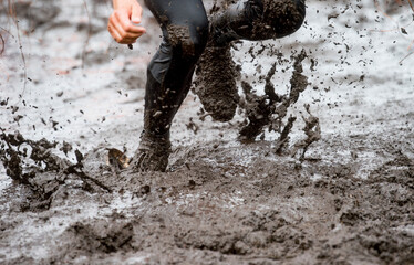 Mud race runner, man running in mud. Runners during extreme obstacle races. Active life and sport...