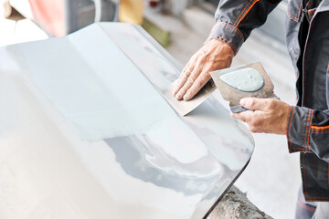 Repairing car body, Application putty close up. The mechanic repair the car. Work after the...