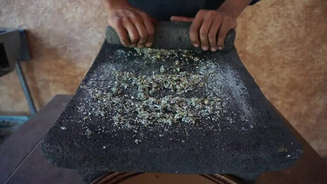 
grinding corn grains into metate, traditional way of making tortilla dough, traditional Mexican food