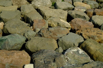 Background from a stone of igneous rock. Wallpaper made of textures of boulders of volcanic origin. Surface of granite, diabase, gabbro interspersed with spar, quartz. Sea shore. Day. Georgia.