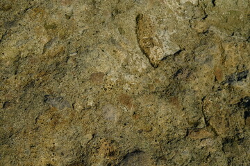 Background from a stone of igneous rock. Wallpaper made of textures of boulders of volcanic origin. Surface of granite, diabase, gabbro interspersed with spar, quartz. Sea shore. Day. Georgia.