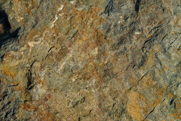 Background from a stone of igneous rock. Wallpaper made of textures of boulders of volcanic origin. Surface of granite, diabase, gabbro interspersed with spar, quartz. Sea shore. Day. Georgia.