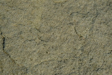Background from a stone of igneous rock. Wallpaper made of textures of boulders of volcanic origin. Surface of granite, diabase, gabbro interspersed with spar, quartz. Sea shore. Day. Georgia.