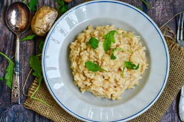 Italian creamy  cheese risotto with mushrooms, parmesan cheese and fresh basil on rustic background